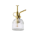 Clear glass bottle with gold metal nozzle on a white background